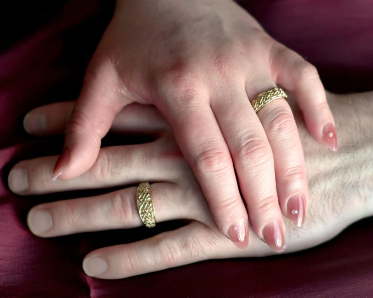 couple wearing custom Celtic love knot male female wedding bands 14k gold
